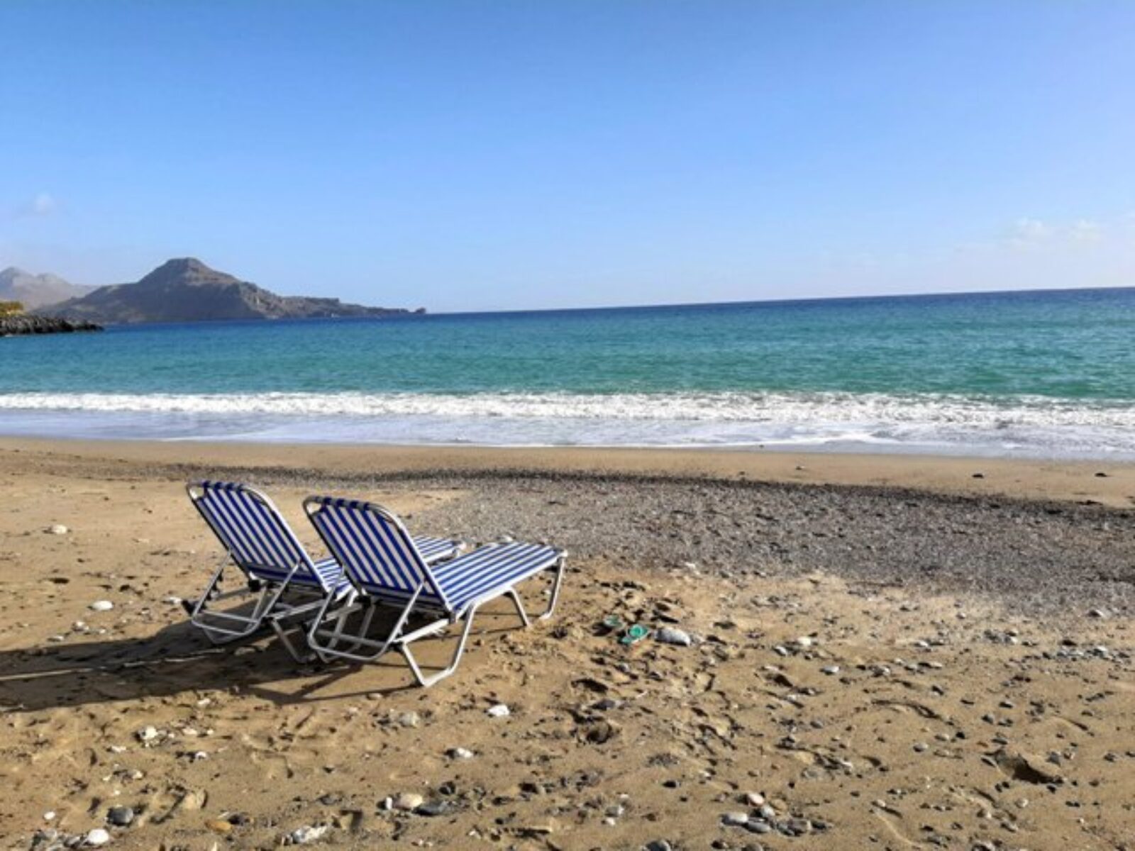 dwa puste leżaki na dzikiej plaży